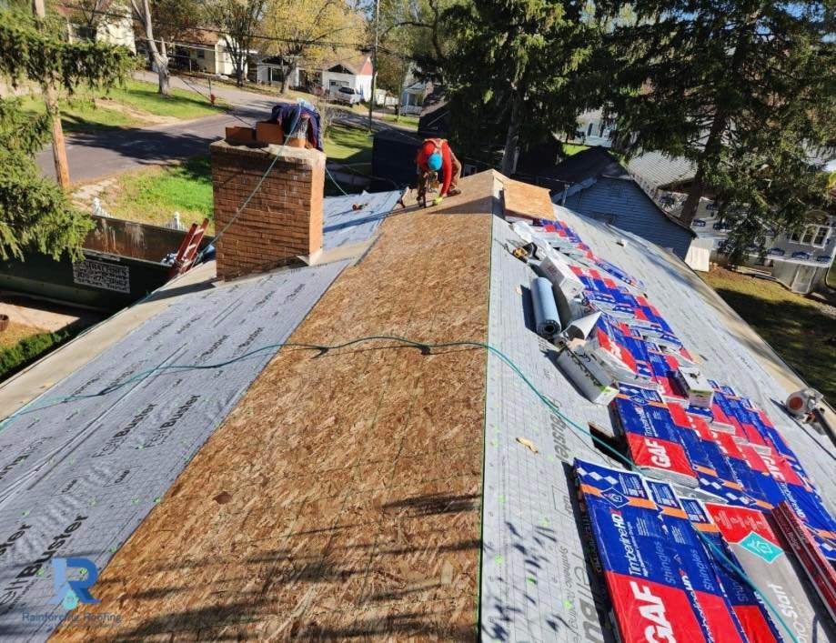 A professional roofer installs new OSB decking and high-performance underlayment on a steep-slope residential roof. GAF Timberline HD shingles and specialized installation materials are used to ensure a code-compliant, durable exterior system